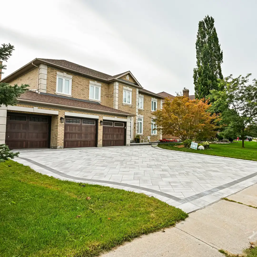 Finished grey interlock driveway, swept clean with all equipment removed, at a triple garage