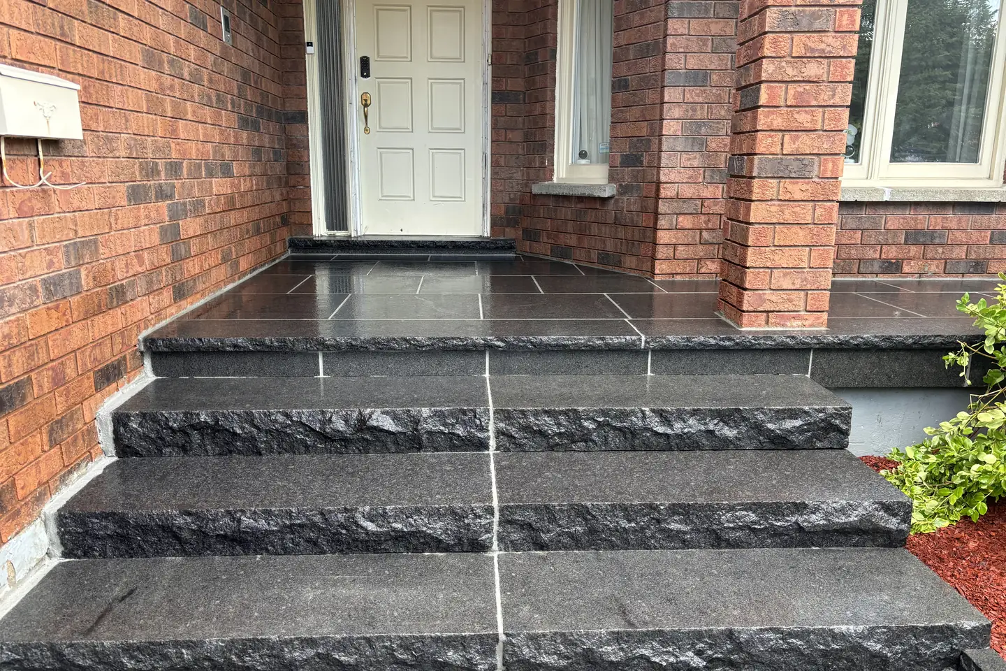 Grey interlock driveway -- large-format pavers, dark charcoal curved border, GTA brick home with double garage