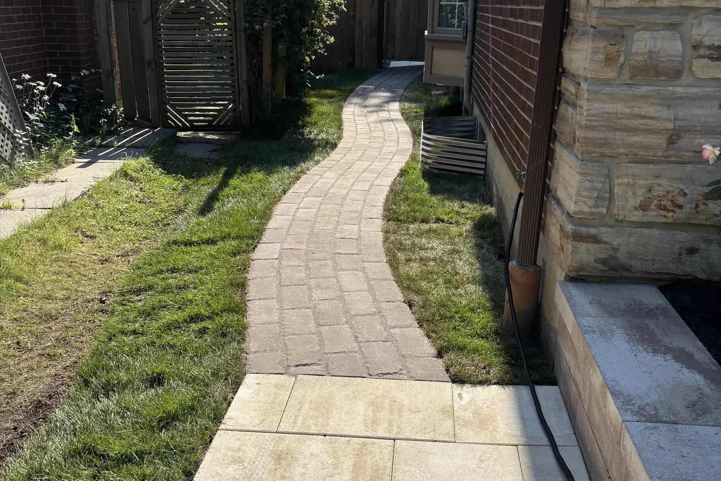 Grey interlock driveway -- large-format pavers, dark charcoal curved border, GTA brick home with double garage