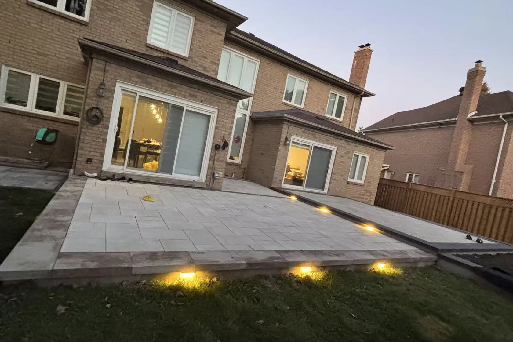 Grey interlock driveway -- large-format pavers, dark charcoal curved border, GTA brick home with double garage